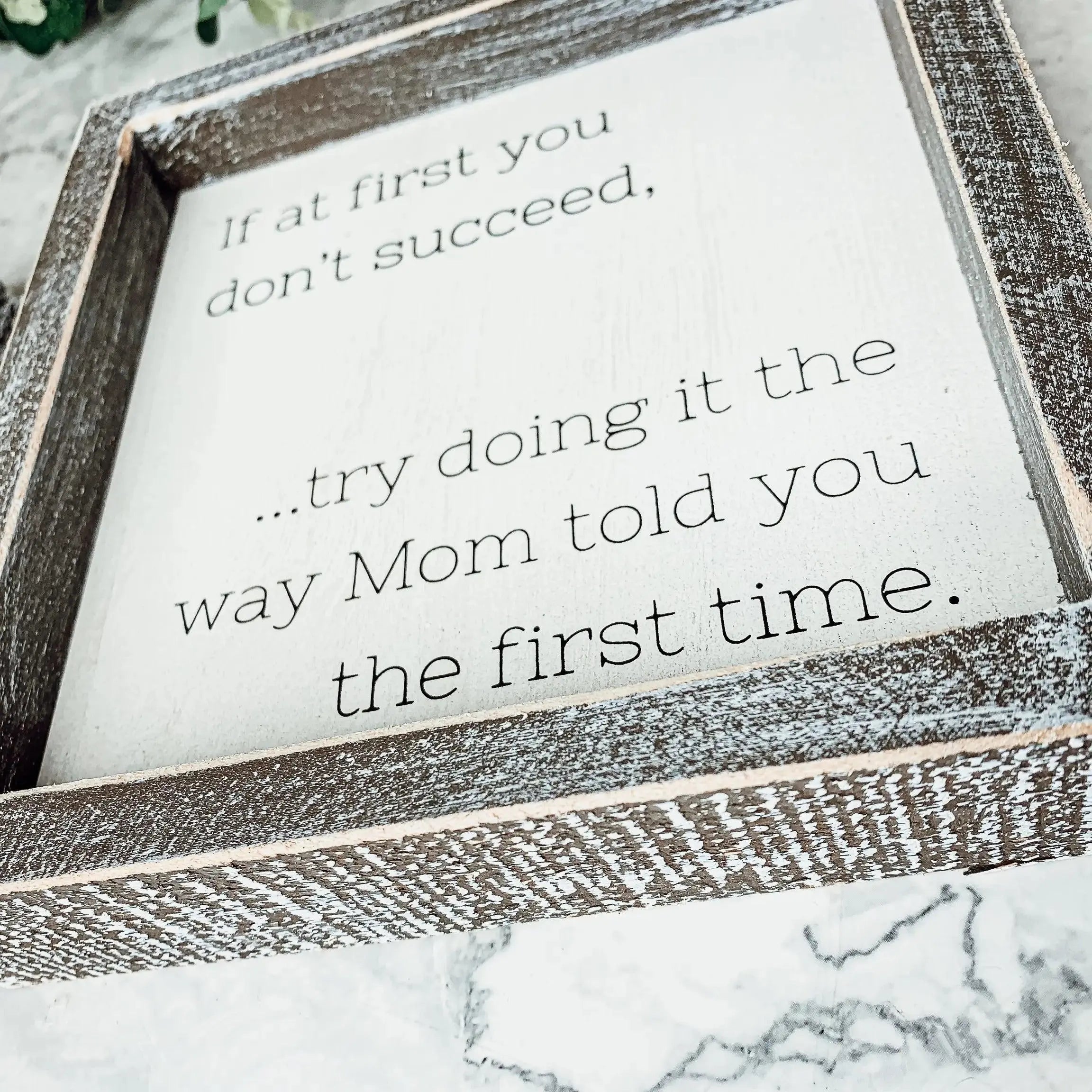 Framed sign with humorous quote on a marble surface