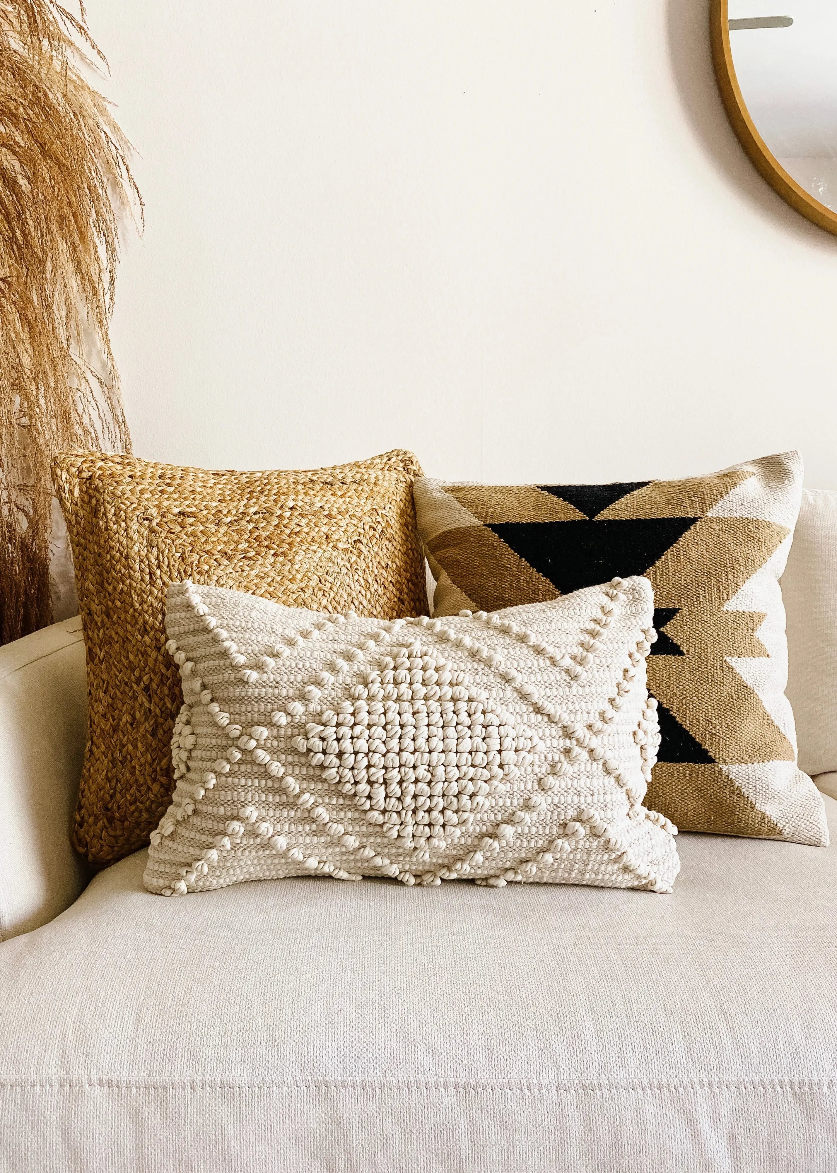 Cozy farmhouse throw pillows with woven textures and geometric patterns on a neutral sofa