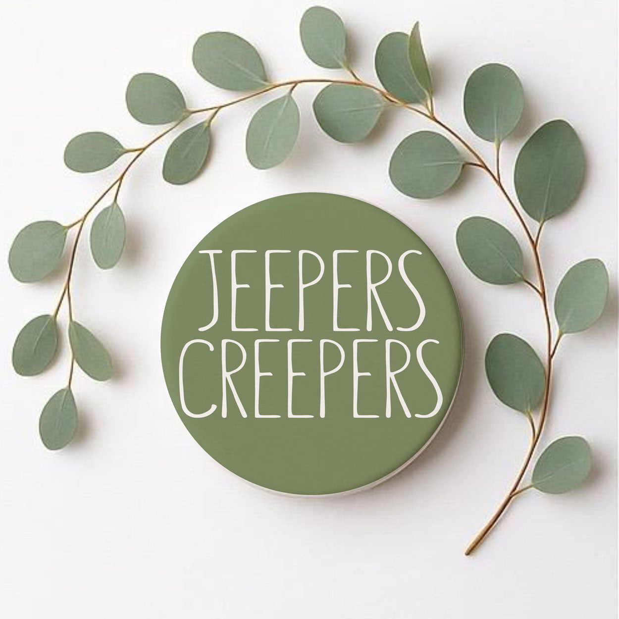 Circular sign with 'Jeeper's Creepers' text surrounded by green leaves on a white background