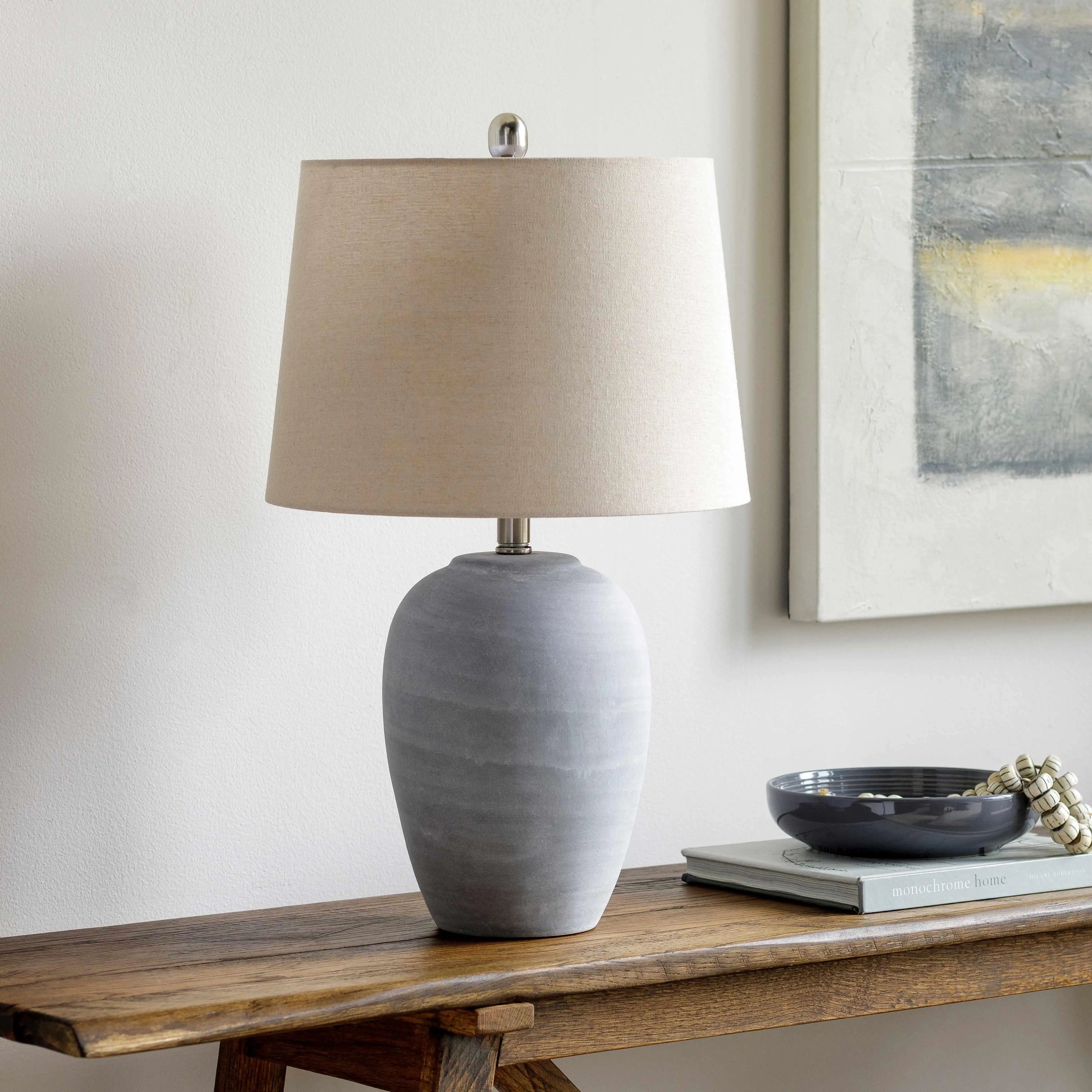 Grey ceramic table lamp with beige linen shade on rustic wood console, farmhouse decor