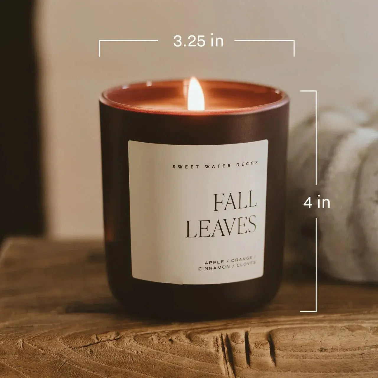 Fall Leaves scented candle with apple, orange, cinnamon, and clove notes, lit on rustic wood surface