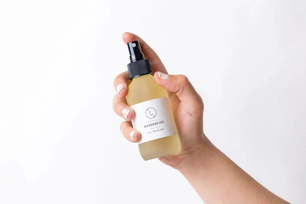 Hand holding bottle of massage oil with spray nozzle, cozy home spa essential for relaxation and self-care