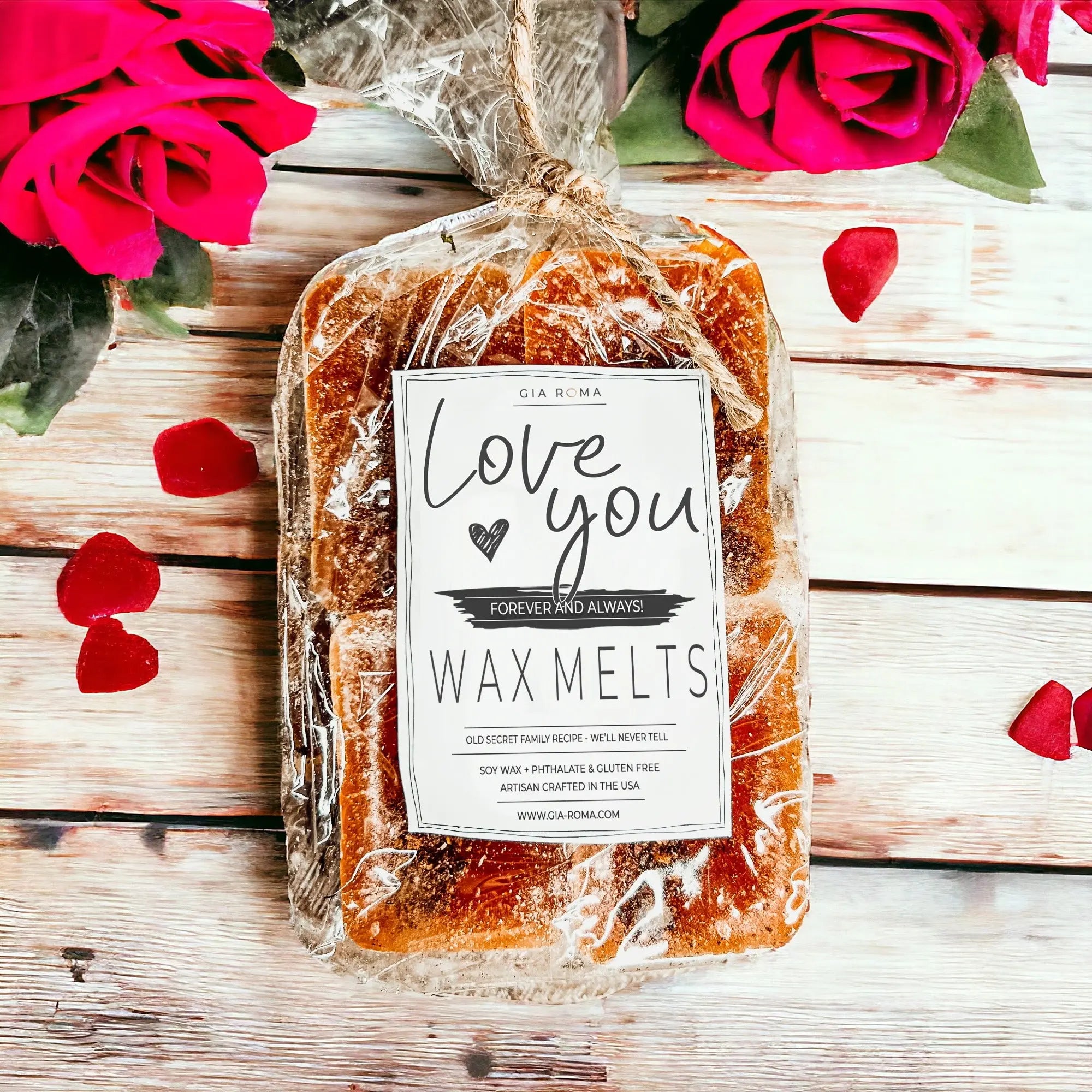 Packaged wax melts with a 'Love you' label on a wooden surface with red roses and petals.