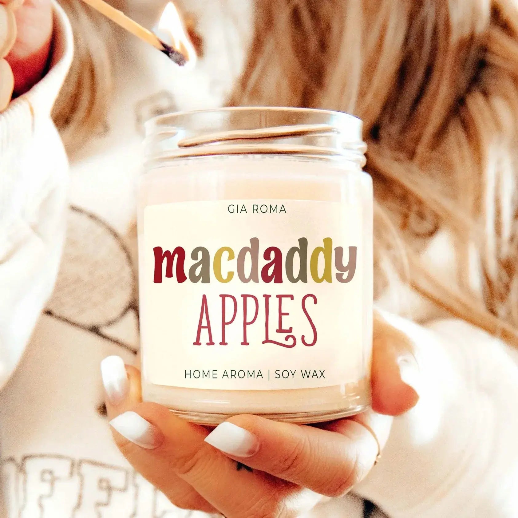 Candle labeled 'macdaddy APPLES' being lit by a person.