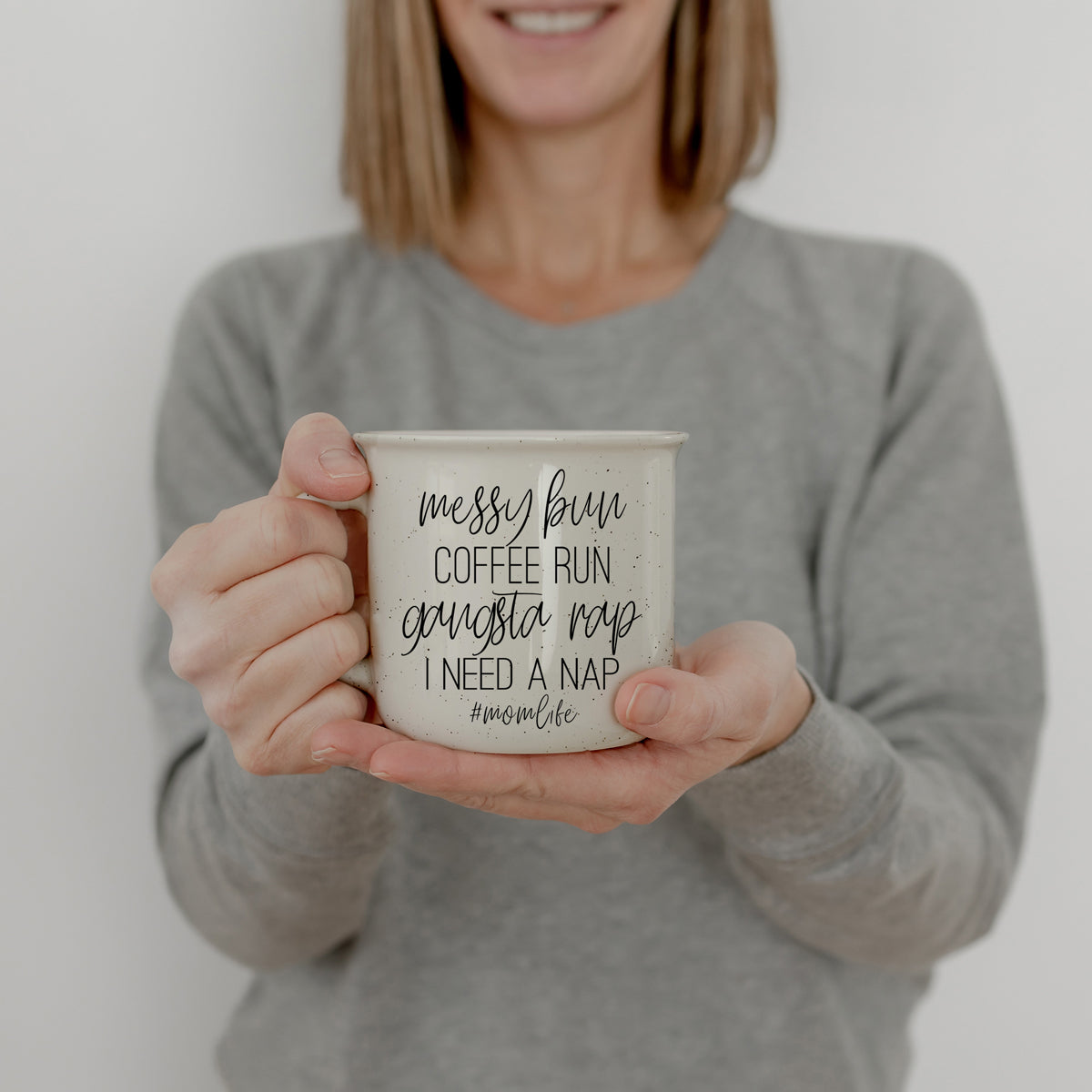 Person holding a mug with text against a plain background