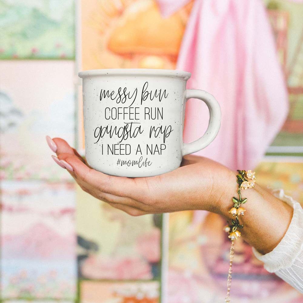 Person holding a mug with text in front of a blurred outdoor background