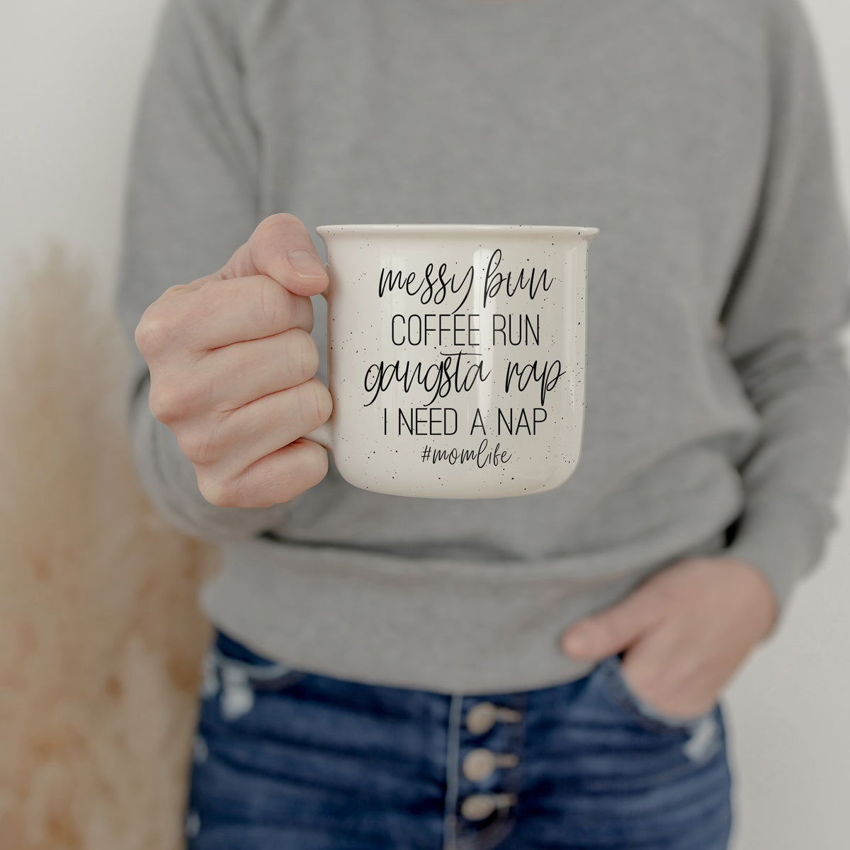 Person holding a mug with text in a casual setting