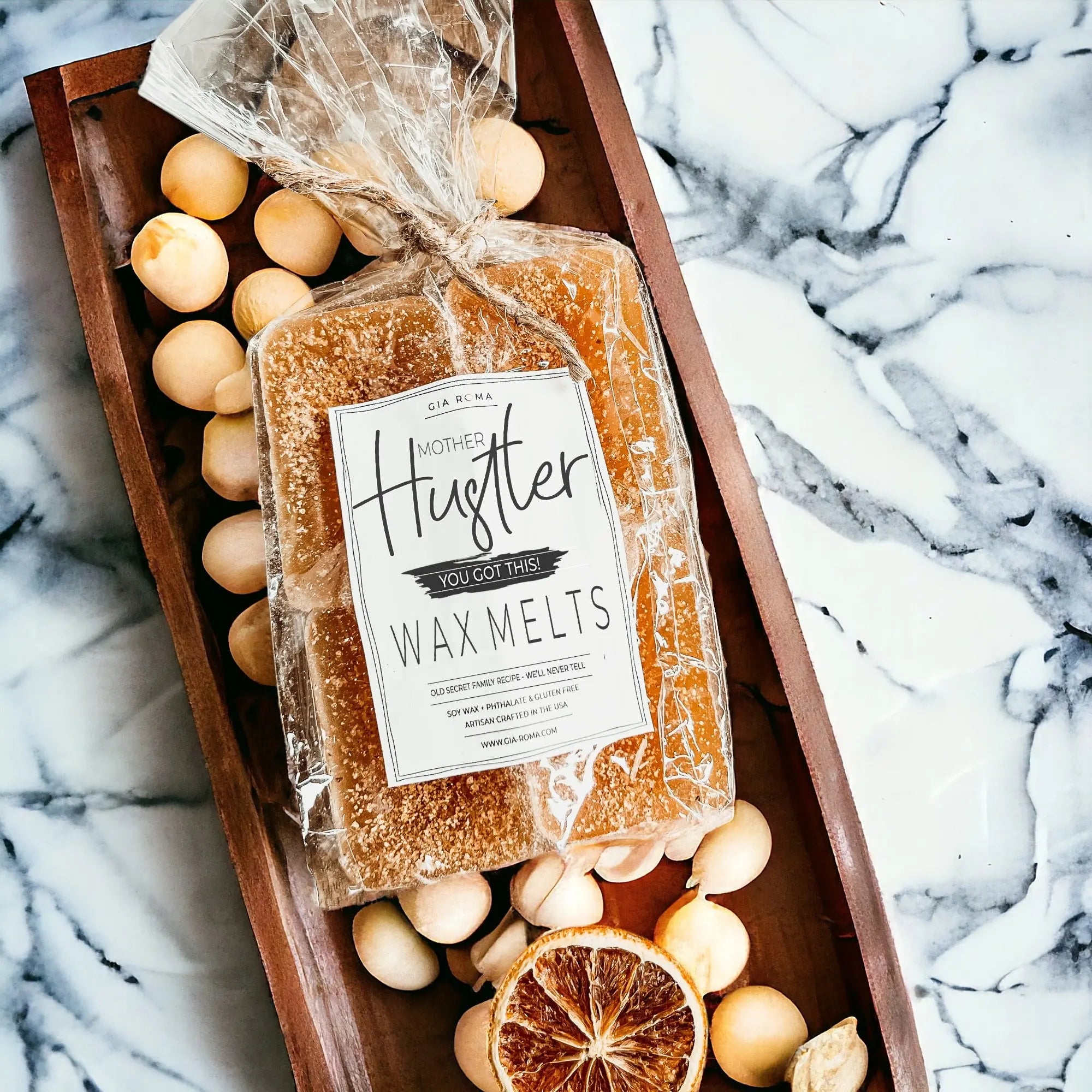 Packaged wax melts with a label on a wooden tray with decorative elements on a marble background
