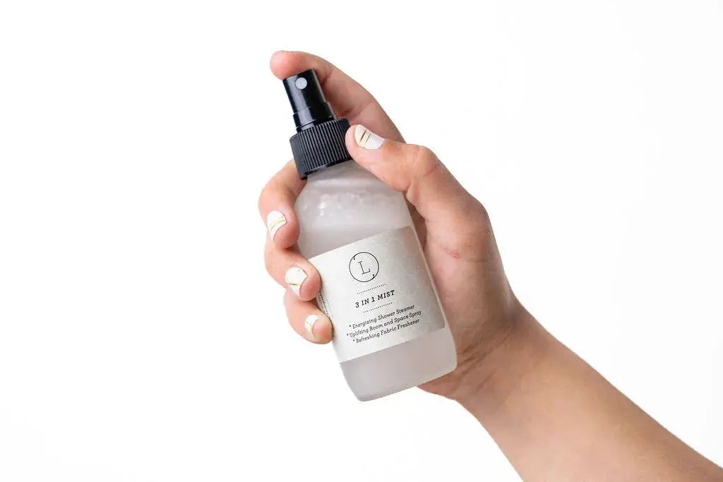Hand holding 3-in-1 mist spray for shower, room, and fabric freshener – cozy home essentials