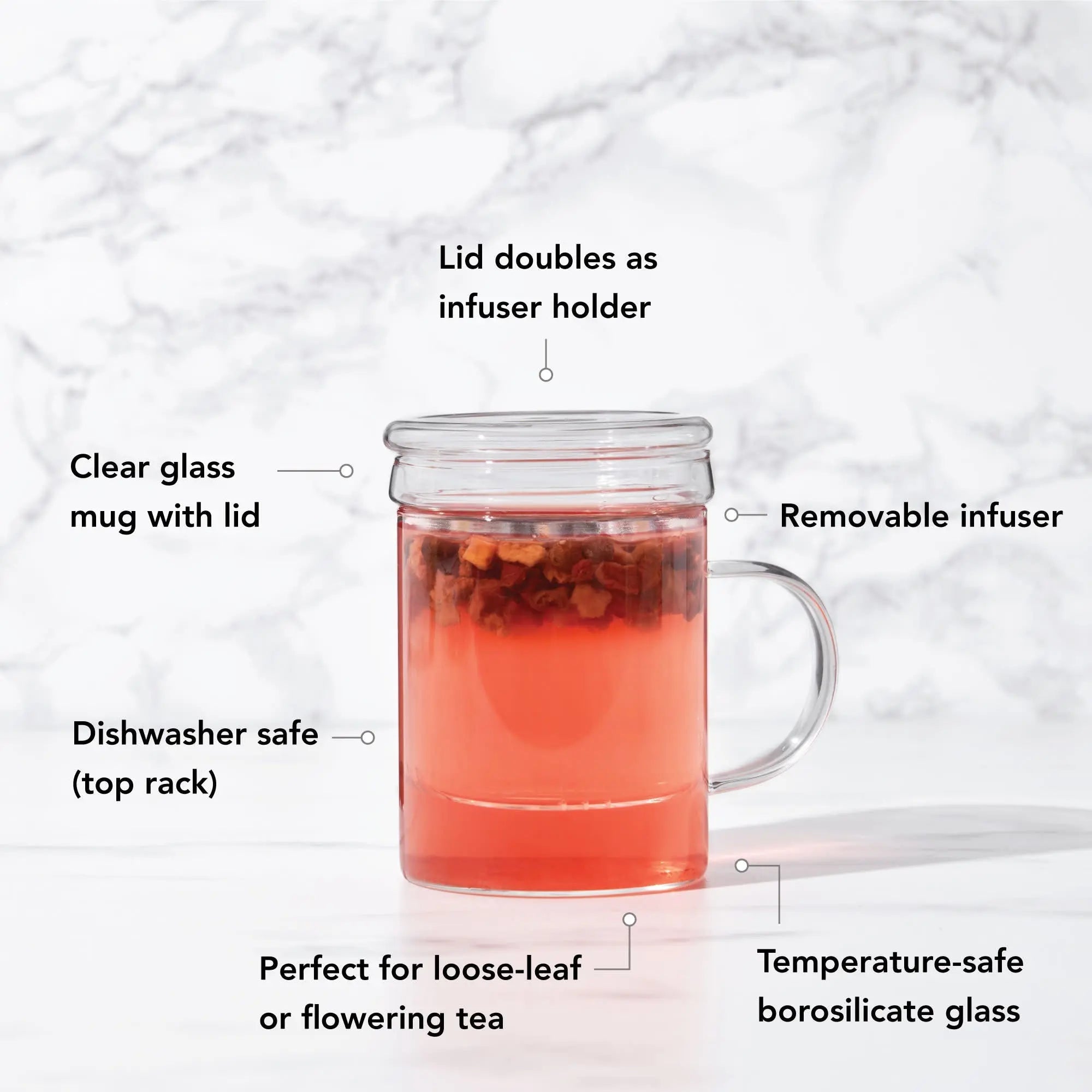Glass mug with lid and removable infuser, filled with tea, on a marble background.