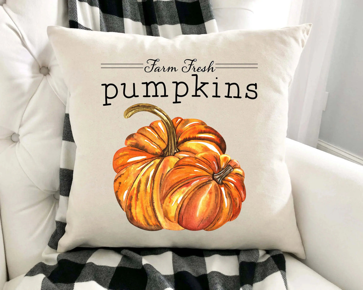 Decorative pillow with a pumpkin design and 'Farm Fresh Pumpkins' text on a white couch.