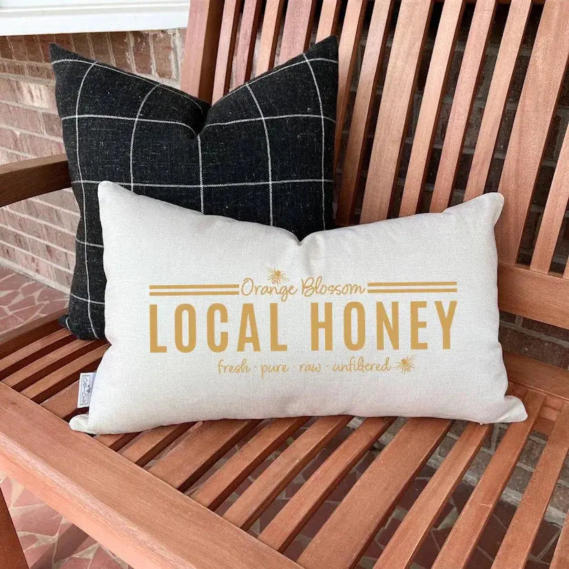 Farmhouse pillow with 'Local Honey' text, cozy cottage decor on wooden bench