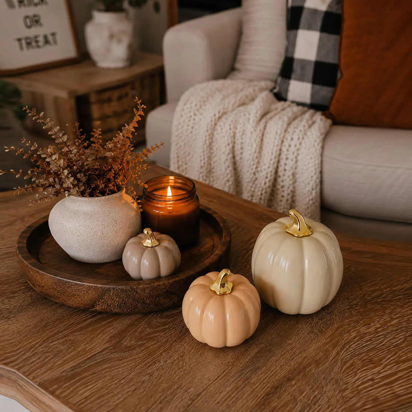 Decorative setup with pumpkins, candles, and a plant on a wooden table.