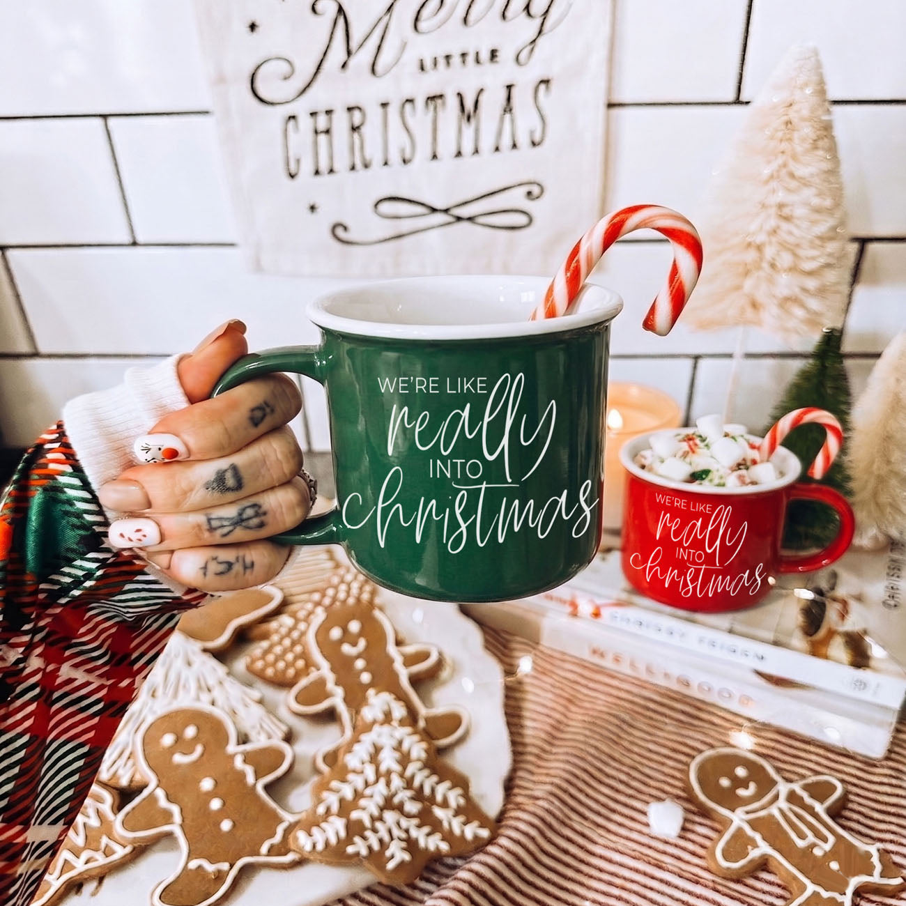 Green mug with 'We're like really into Christmas' text, candy cane, and gingerbread cookies on a festive background.