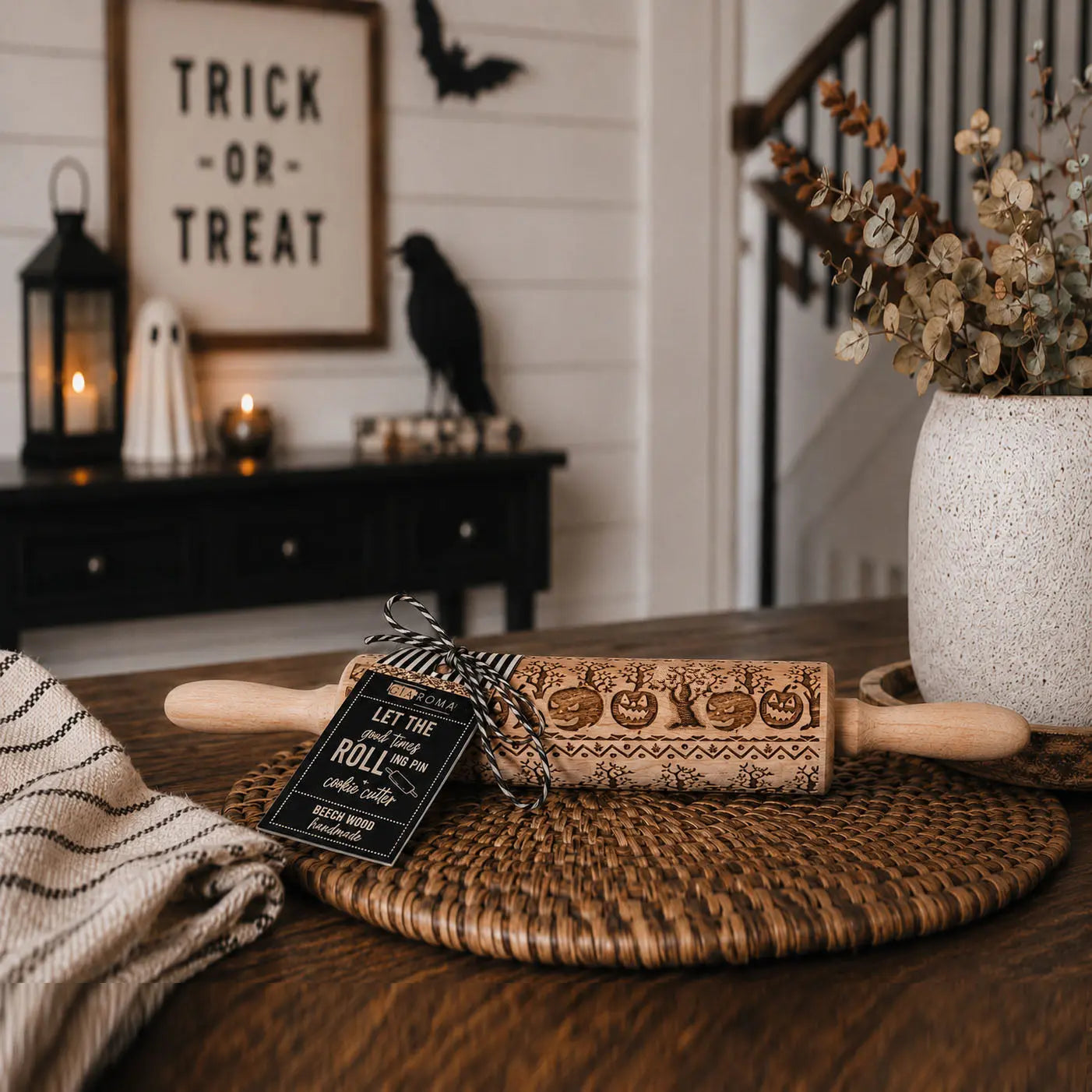 Wooden rolling pin with Halloween-themed design on a table, with 'Trick or Treat' sign in the background.