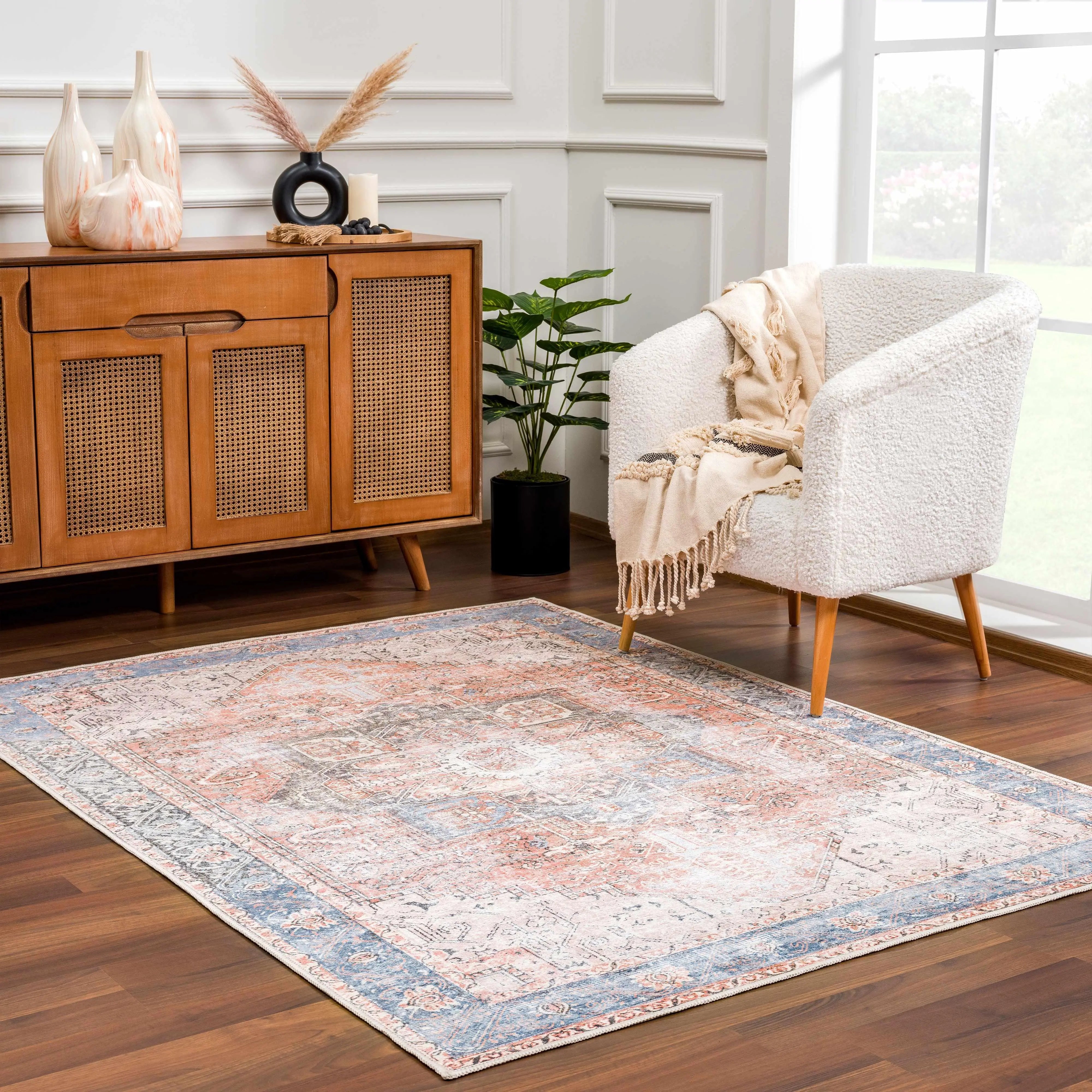 Cozy living room with vintage rug, white armchair, and wooden sideboard for farmhouse decor