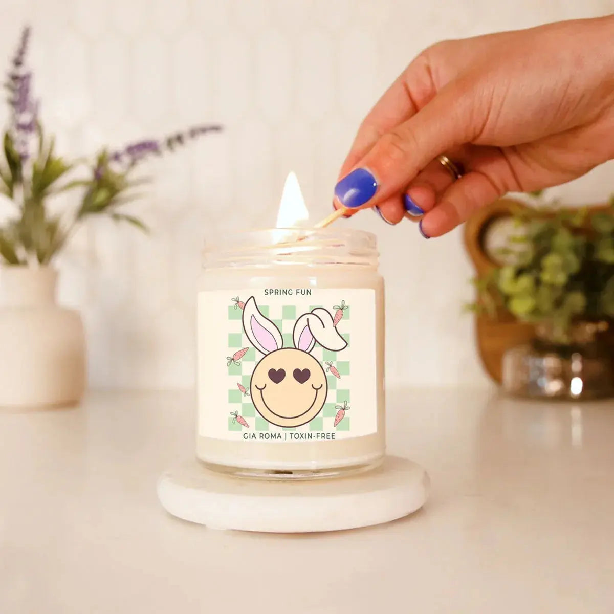 Hand lighting a candle with a cute label on a neutral background