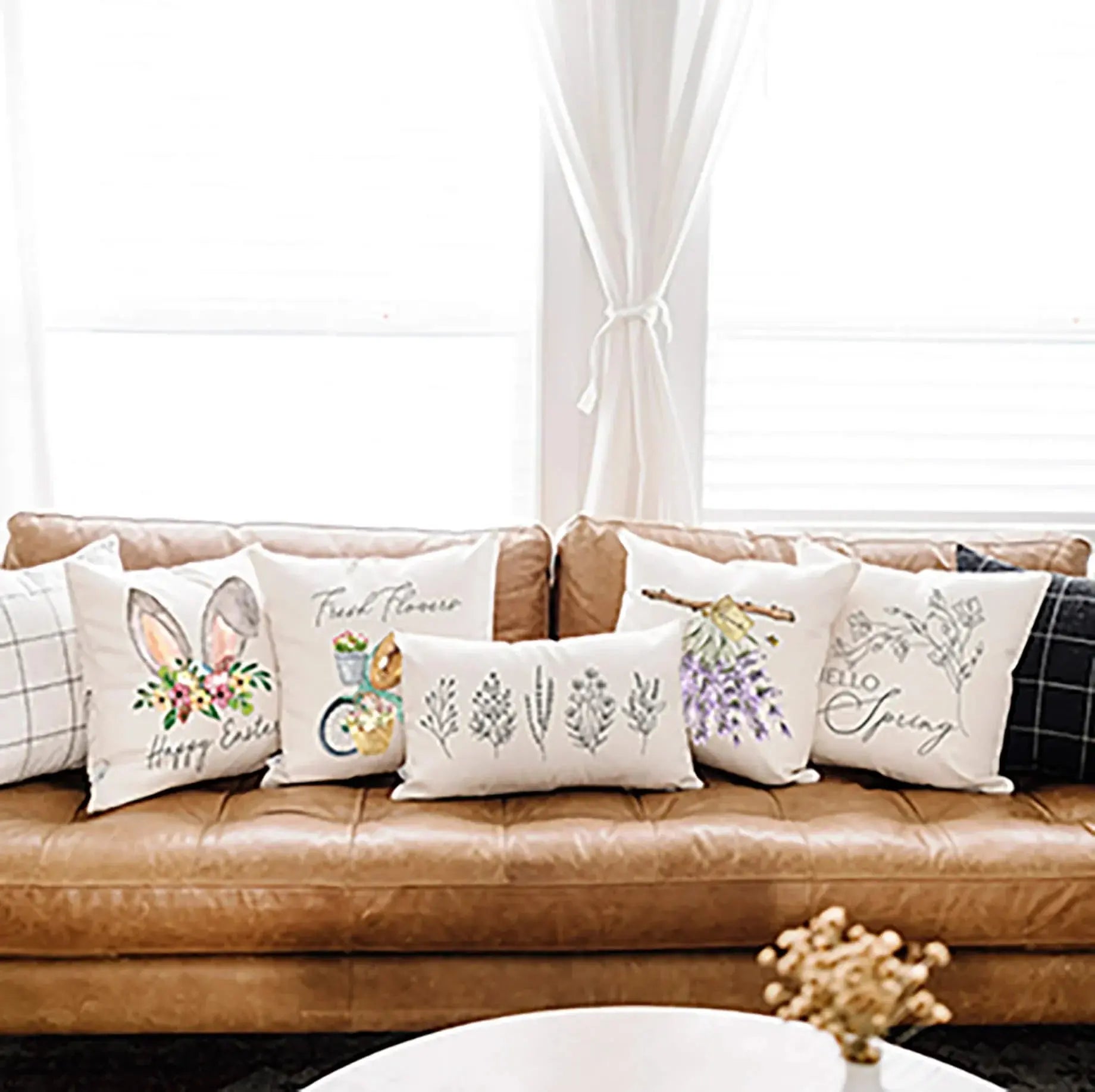 Spring and Easter throw pillows with floral, bunny, and bicycle designs on a cozy leather sofa
