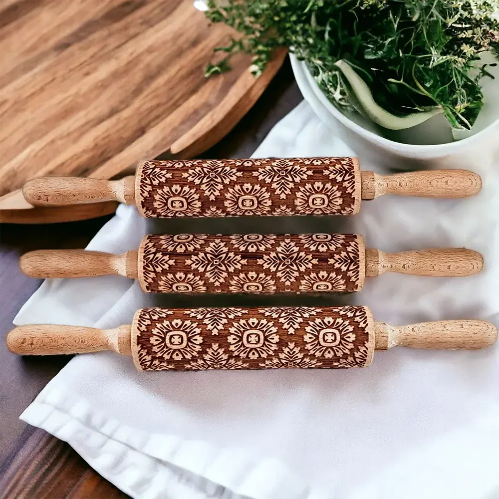 Three wooden rolling pins with embossed patterns on a white surface.