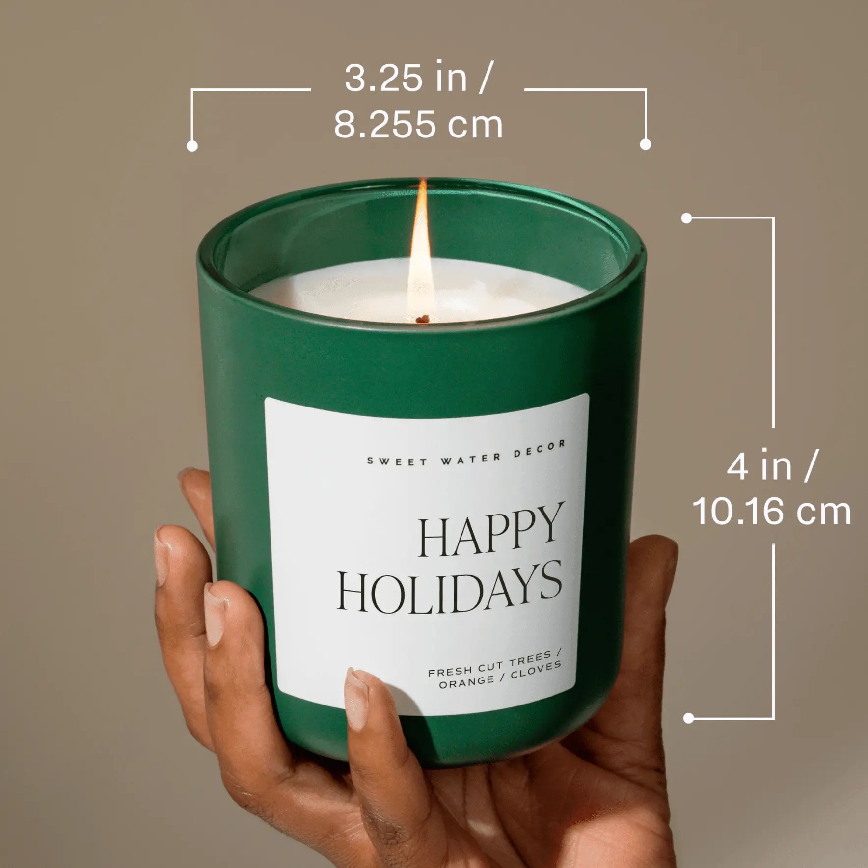 Hand holding a 'Happy Holidays' candle with dimensions displayed