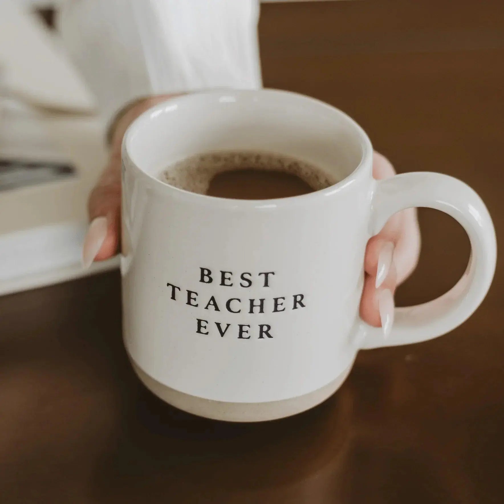 White ceramic mug with 'Best Teacher Ever' text, held by hand, cozy farmhouse style gift