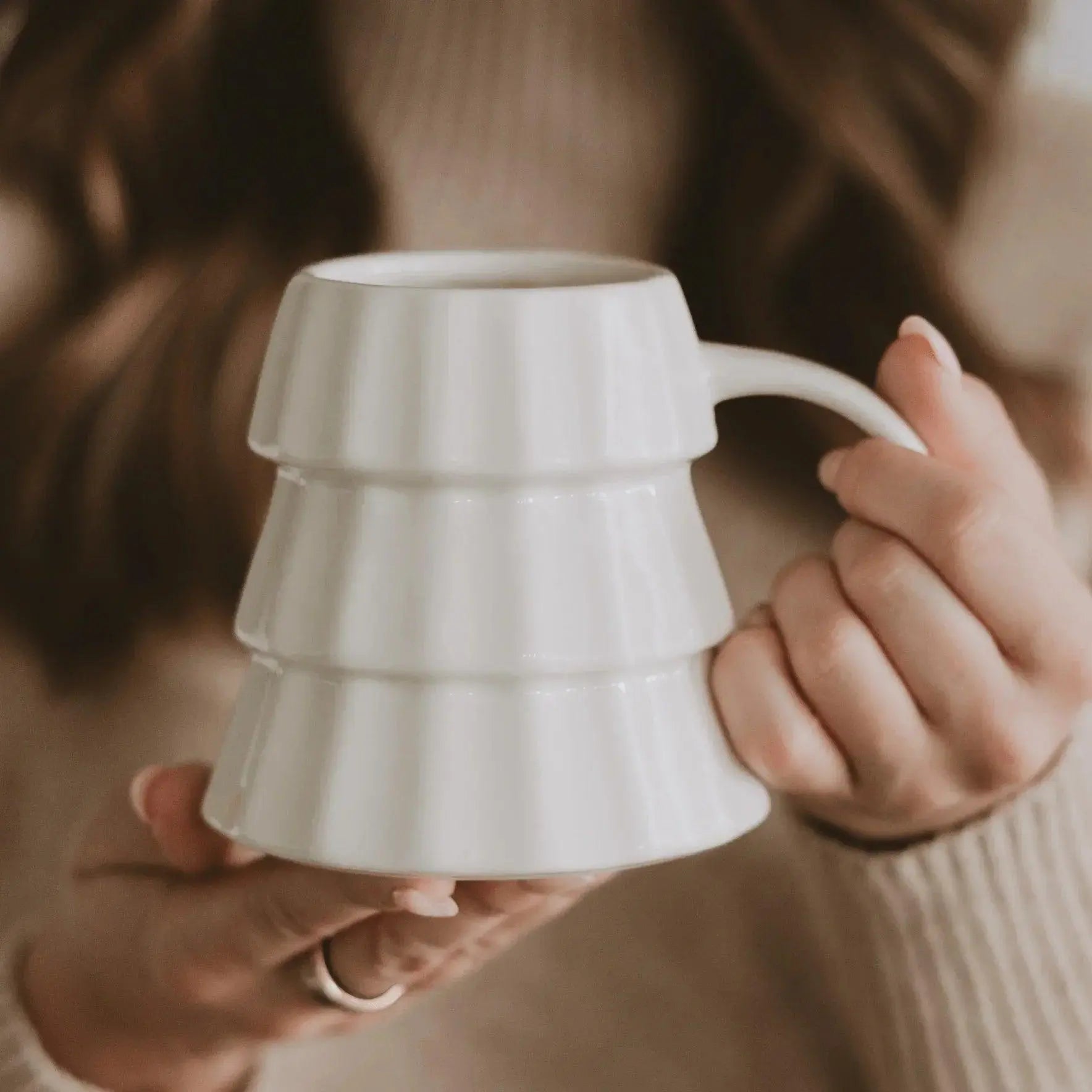 White tiered ceramic mug held in hands, cozy farmhouse style home decor