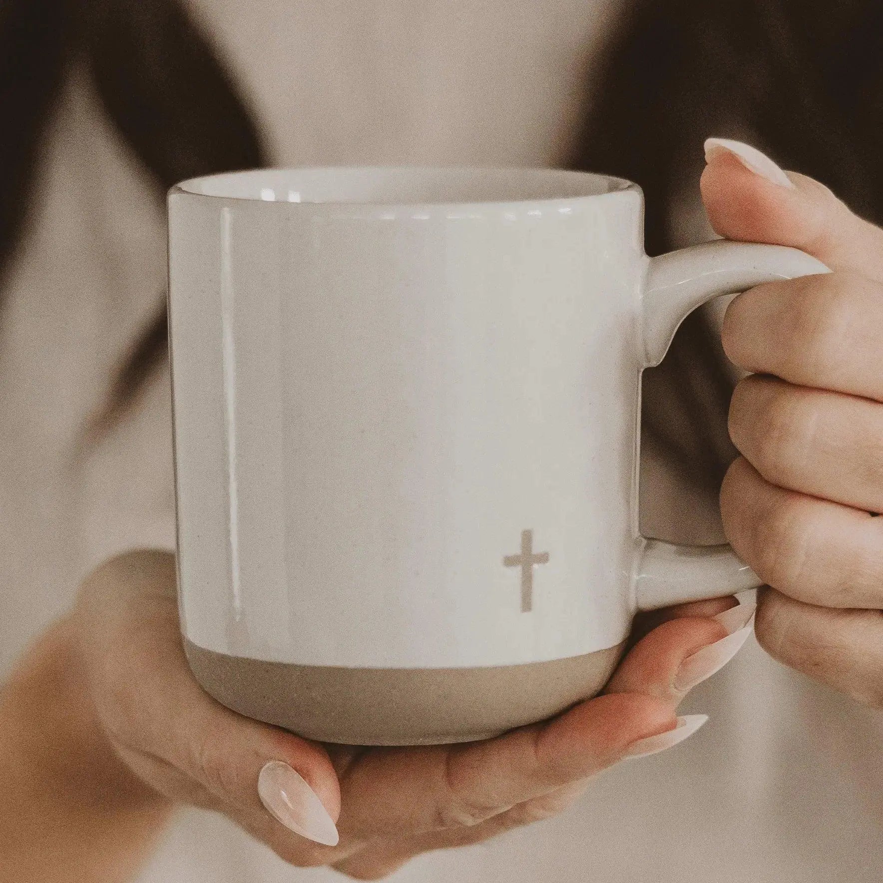 White ceramic mug with cross design, held in hands, cozy farmhouse style home decor