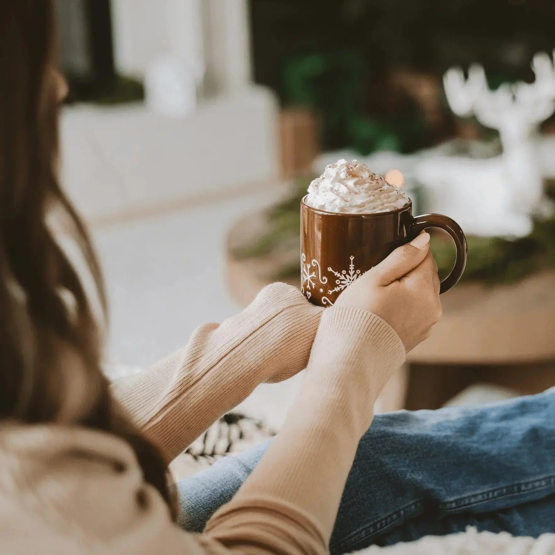Cozy winter mug with whipped cream, snowflake design, held in hands for farmhouse holiday decor