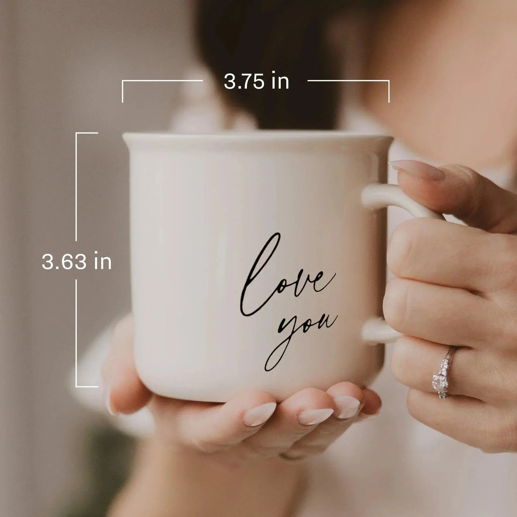 White ceramic mug with 'love you' script, cozy farmhouse style, held gently in hands, 3.63 x 3.75 inches