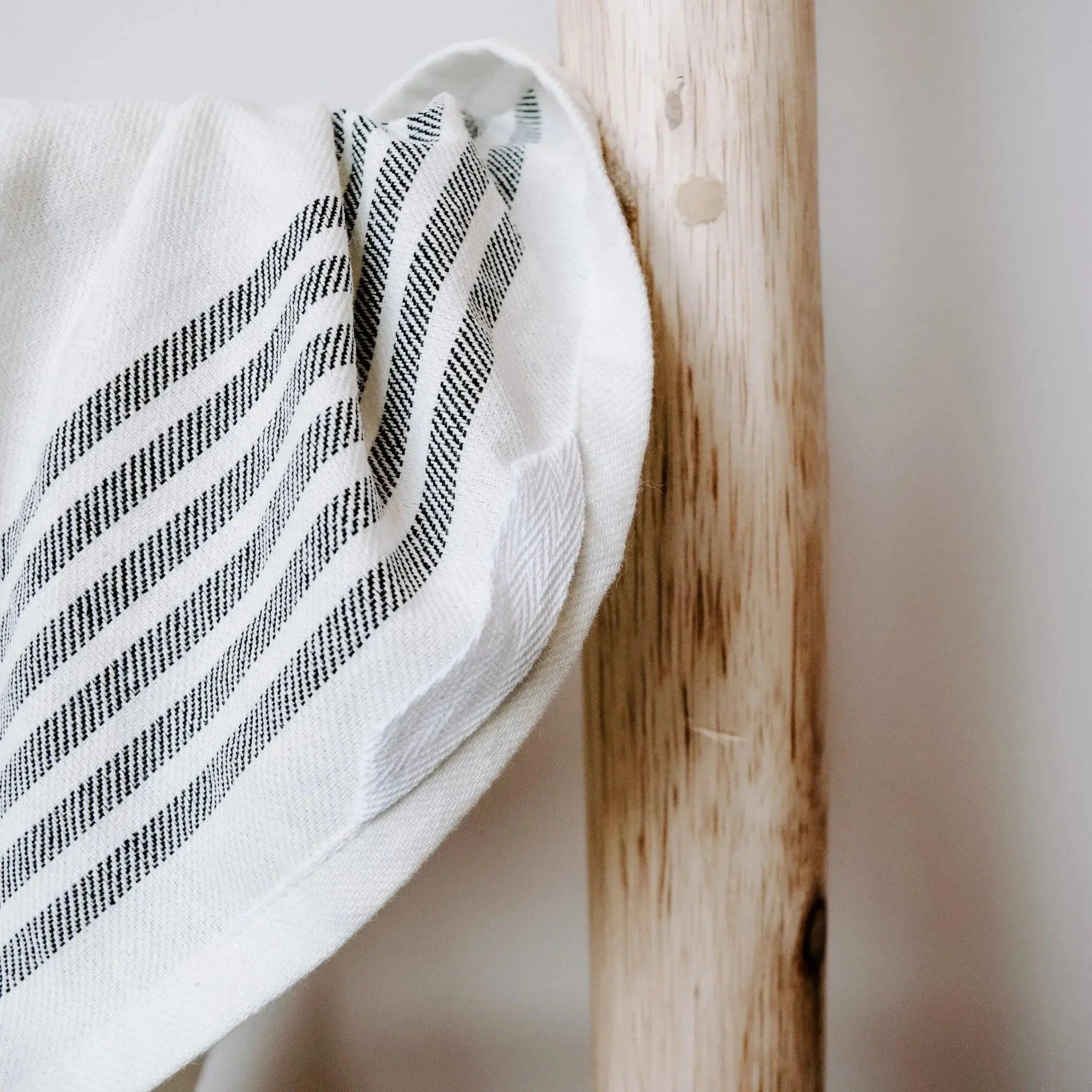 White farmhouse throw blanket with black striped pattern draped over wooden bedpost, cozy cottage decor