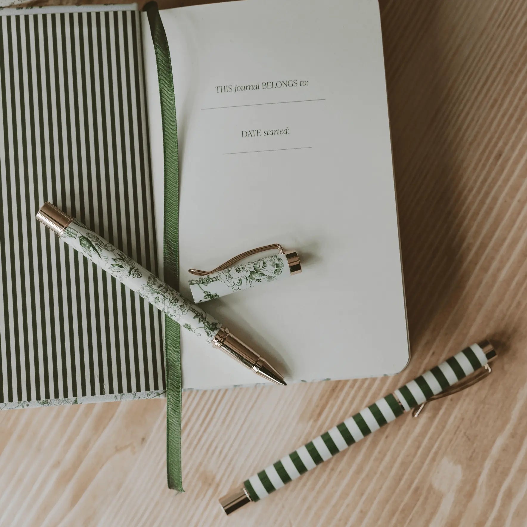Journal with a green ribbon and matching pen on a wooden surface