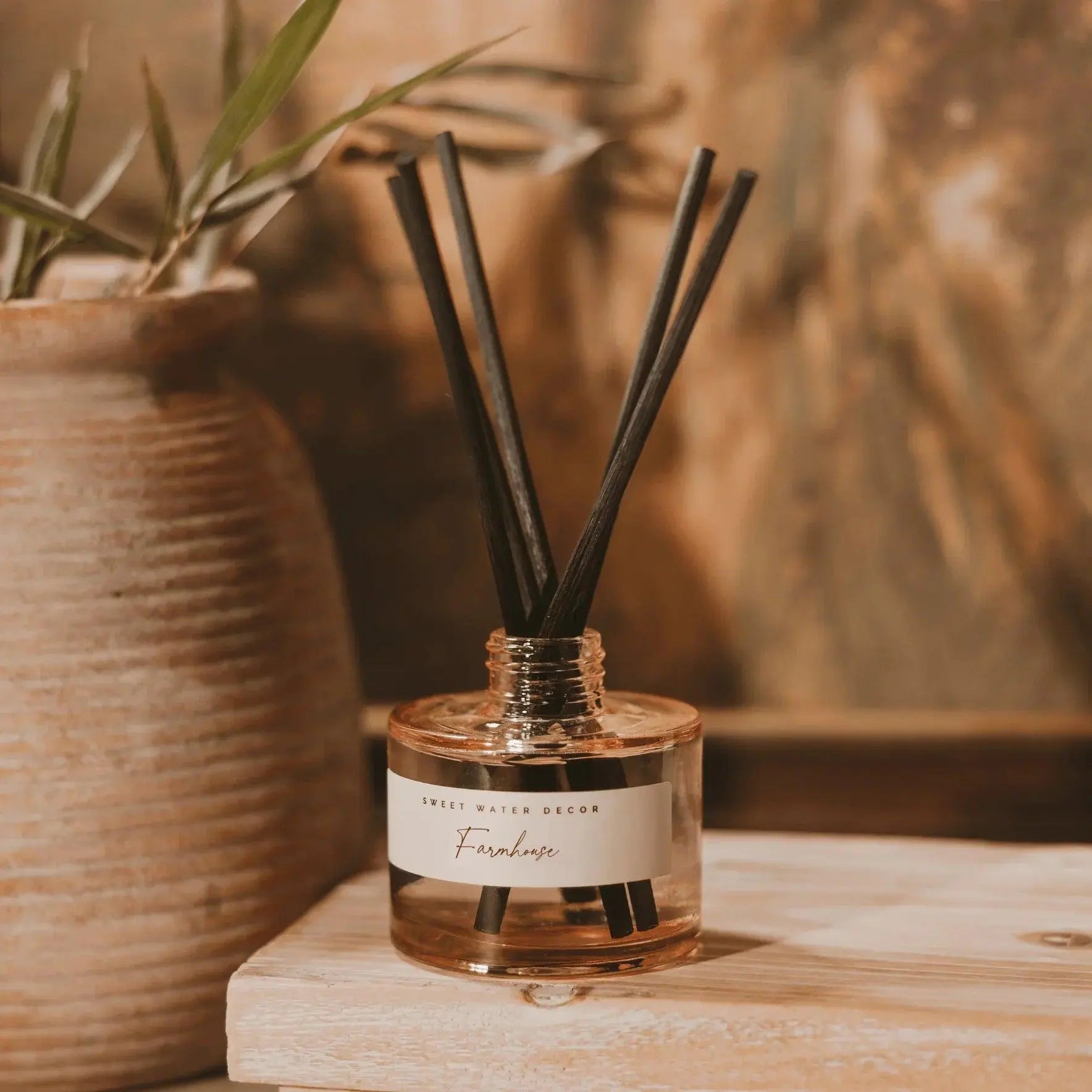 Farmhouse reed diffuser with black sticks, cozy home decor on wooden surface