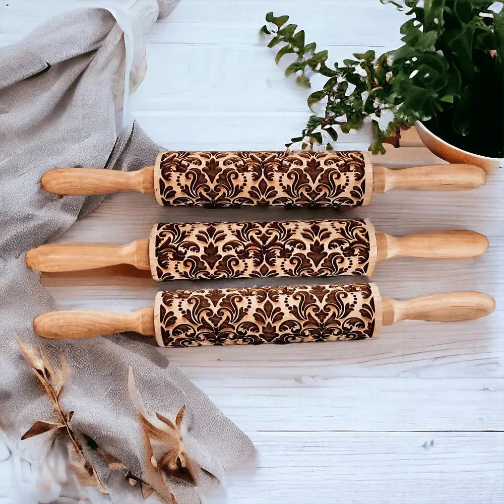 Three wooden rolling pins with embossed patterns on a light wooden surface.