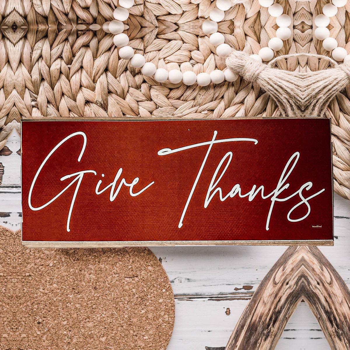 Decorative sign with 'Give Thanks' text on a rustic background