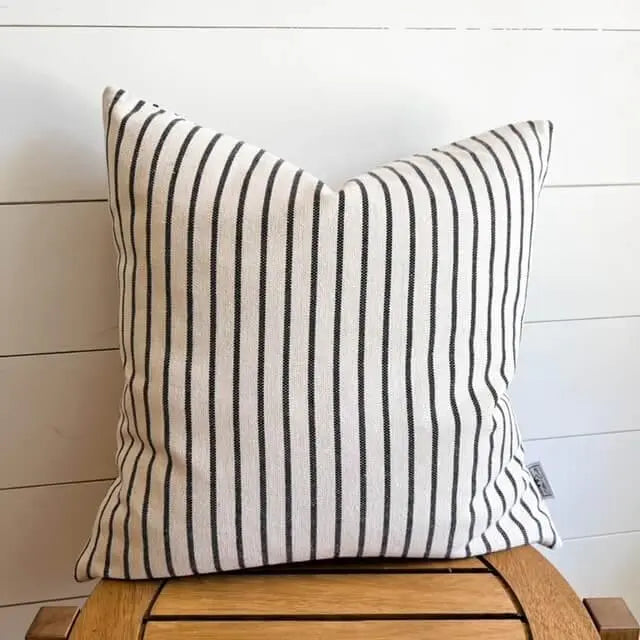 Black and white striped farmhouse pillow on wooden chair, cozy cottage decor accent
