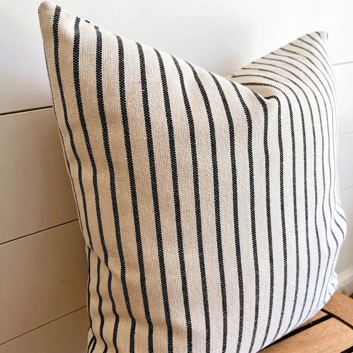 Black and white striped farmhouse pillow on wooden bench, cozy cottage decor accent