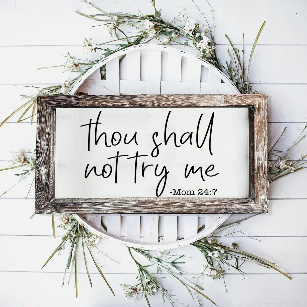 Wooden framed sign with 'thou shall not try me' text on a white background with greenery.