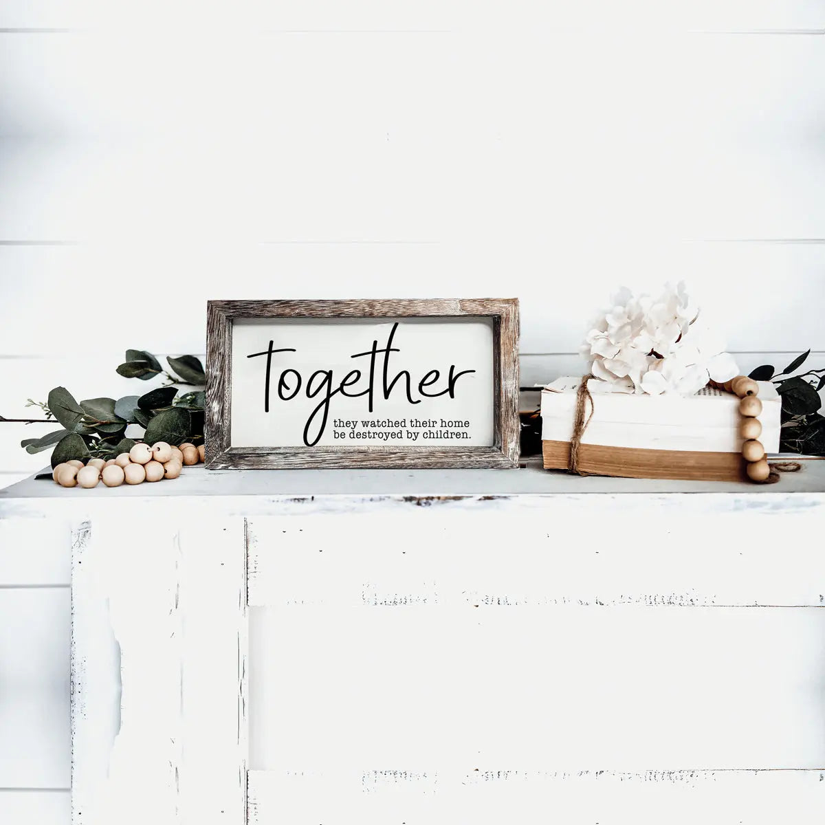 Framed sign with 'Together' text on a white surface with decorative elements.
