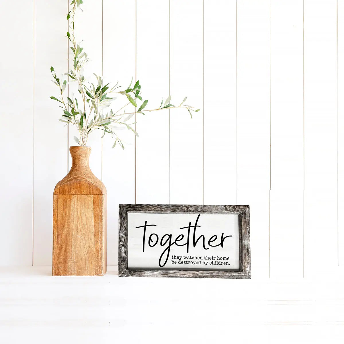 Wooden vase with greenery next to a framed sign with the word 'Together' on a white background.