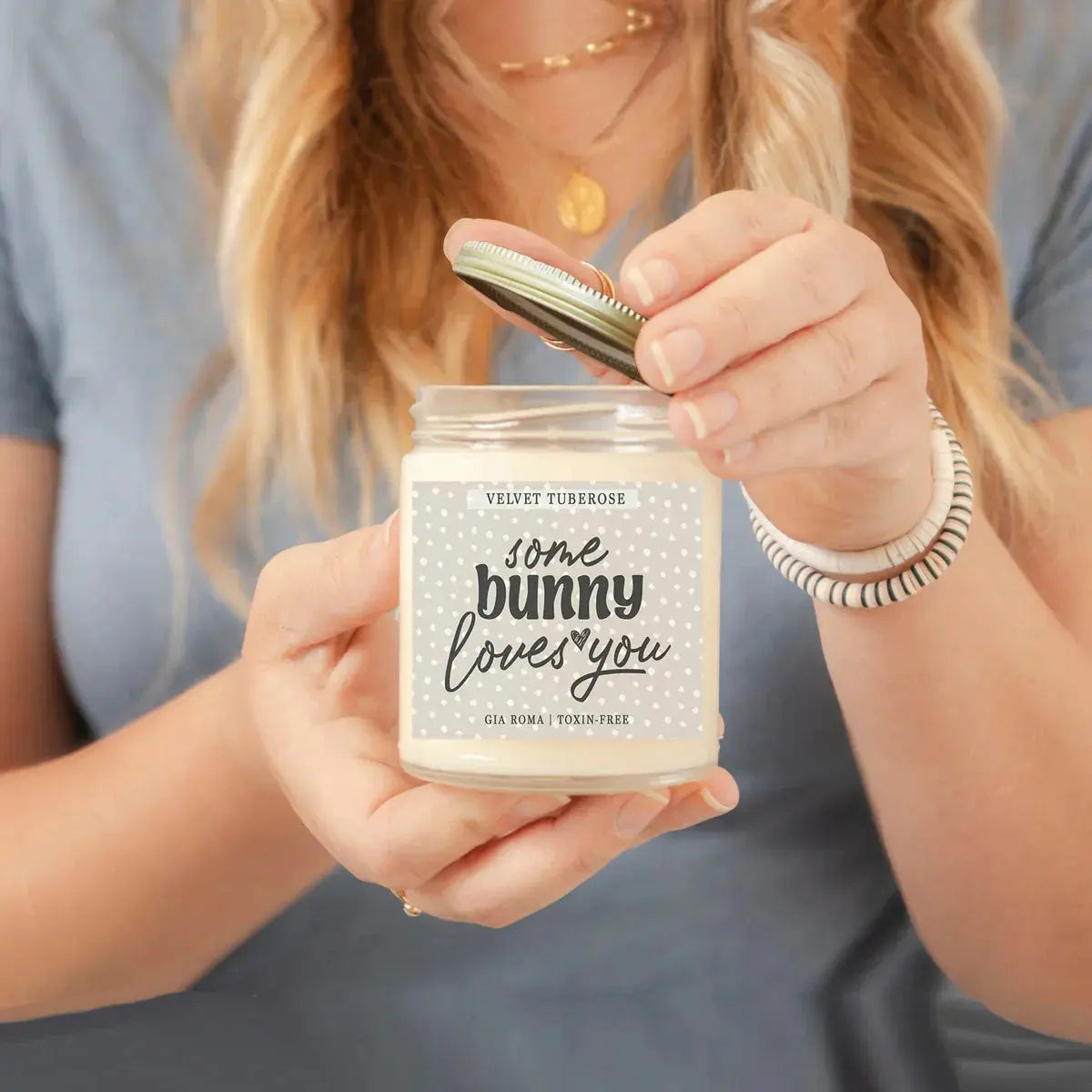 Person holding a candle labeled 'some bunny loves you' with a blurred background