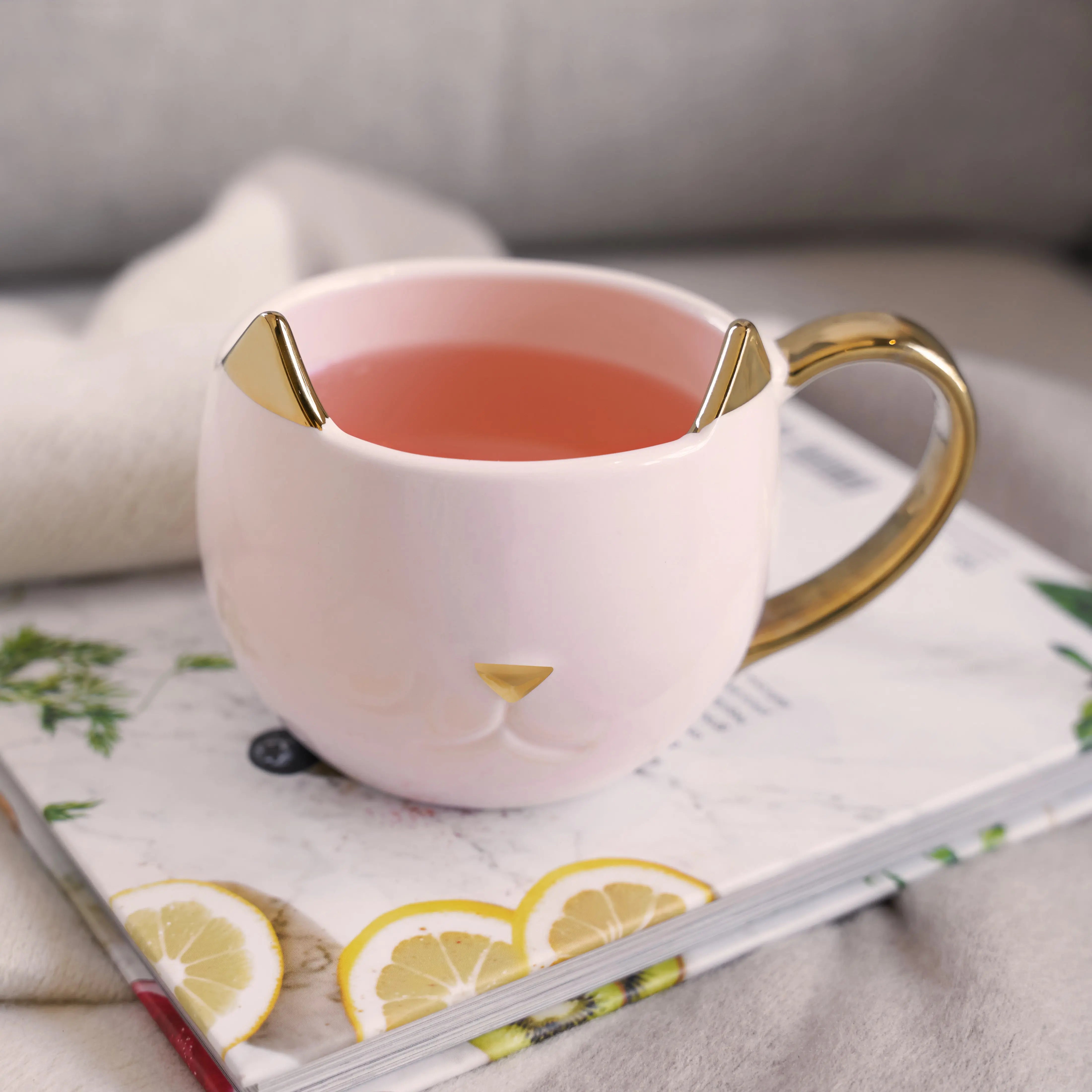 Pink cat-shaped mug with gold accents on a magazine