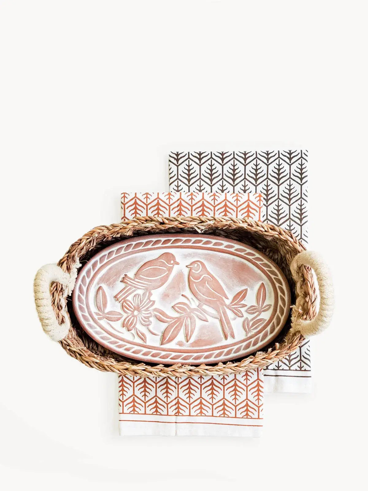 Rustic ceramic bird platter in woven tray with patterned napkins, farmhouse kitchen decor