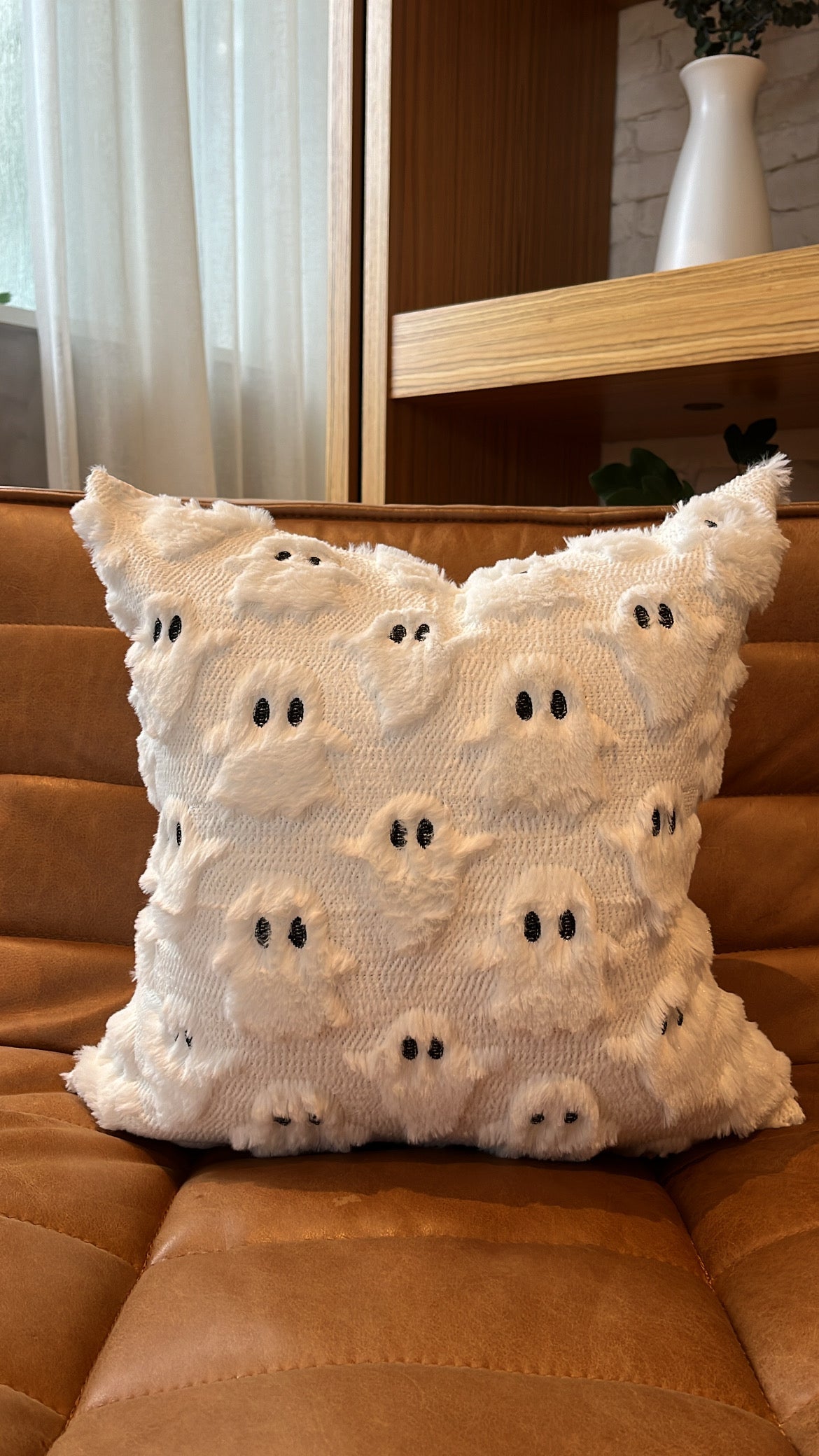 Decorative pillow with ghost pattern on a brown couch