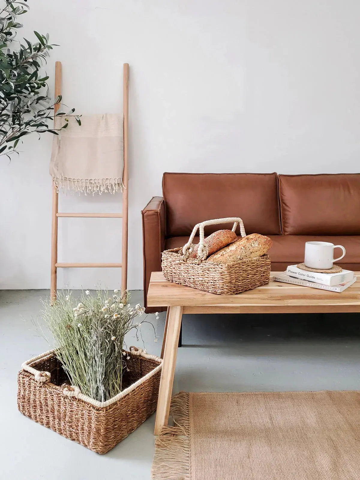 Cozy farmhouse living room with wicker baskets, bread, books, and dried flowers on wooden coffee table