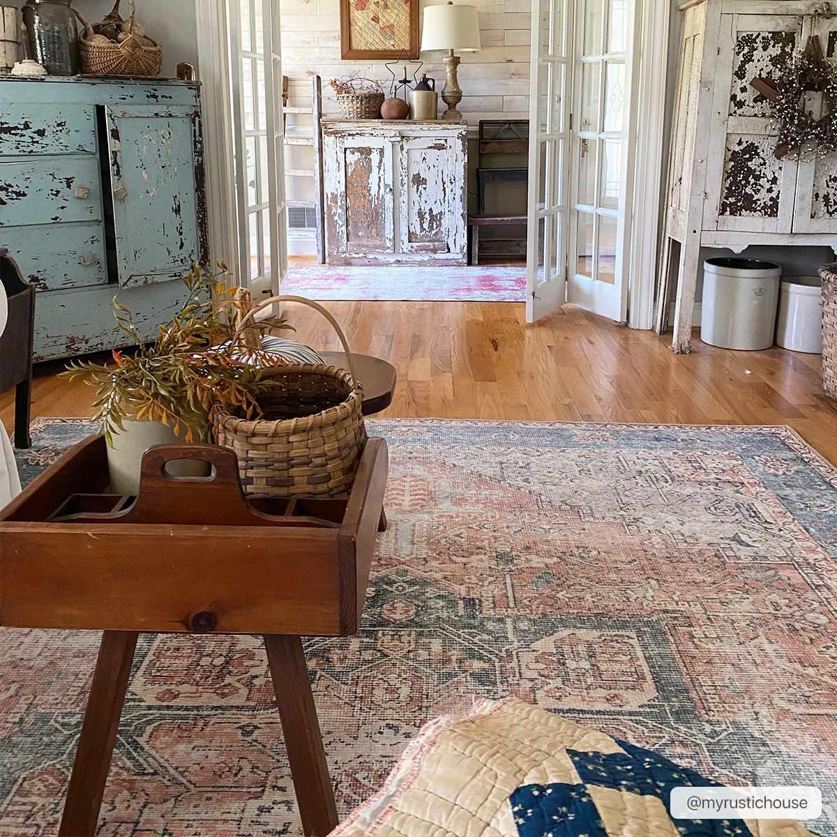 Cozy farmhouse living room with distressed furniture, vintage rug, wicker basket, and rustic decor accents