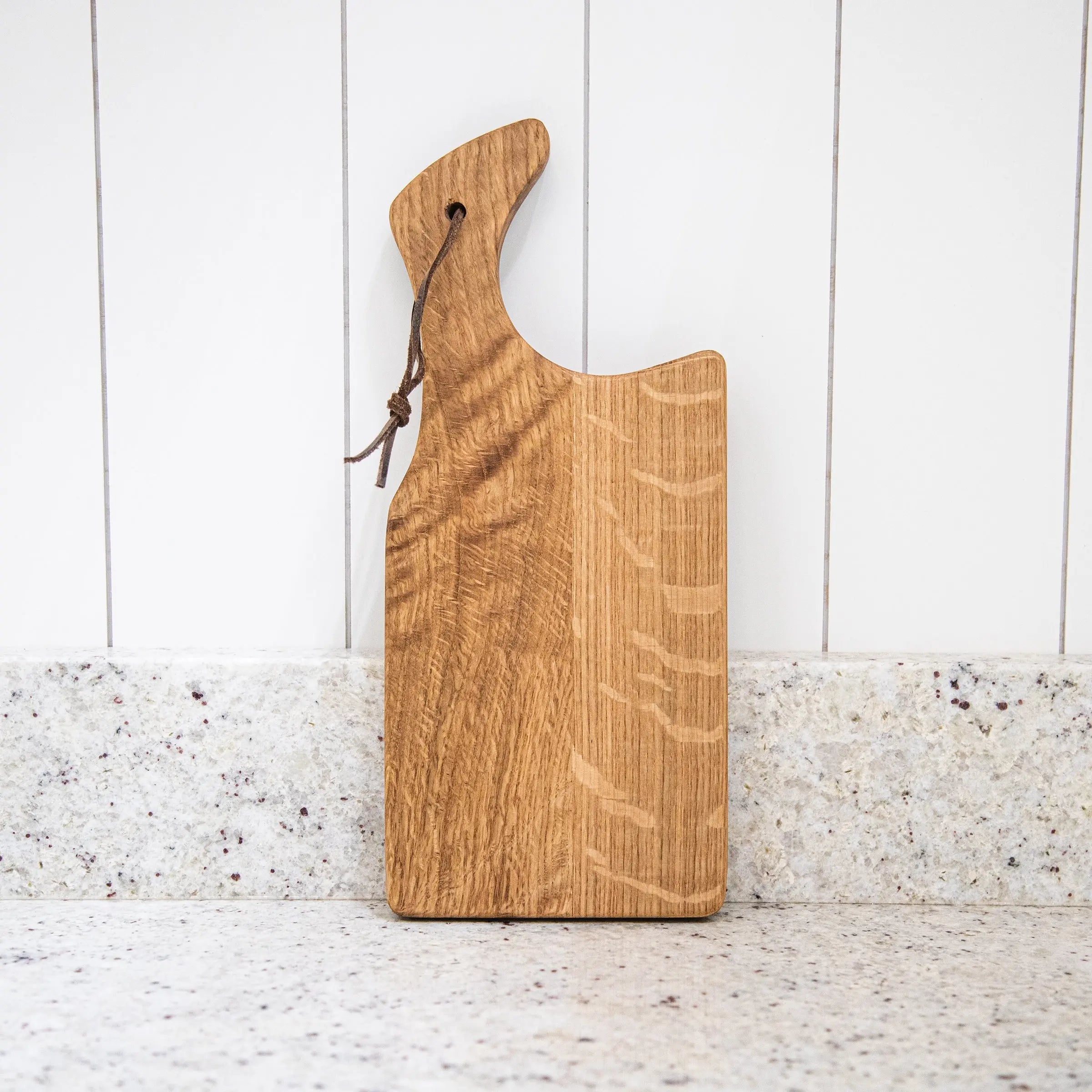 Wooden cutting board with a handle on a white wooden surface
