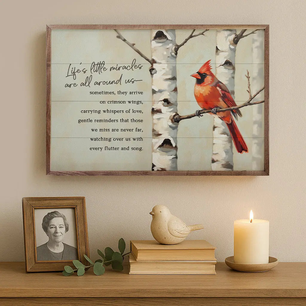 Framed artwork with a cardinal bird on a branch, surrounded by decorative items on a wooden surface.