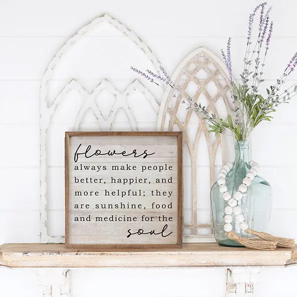 Decorative shelf with a framed quote, vase with flowers, and decorative items.