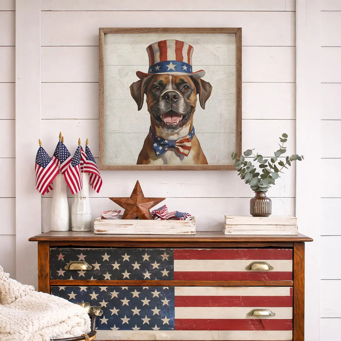 Decorative dresser with American flag design, framed picture of a dog, and small American flags on a white wall.