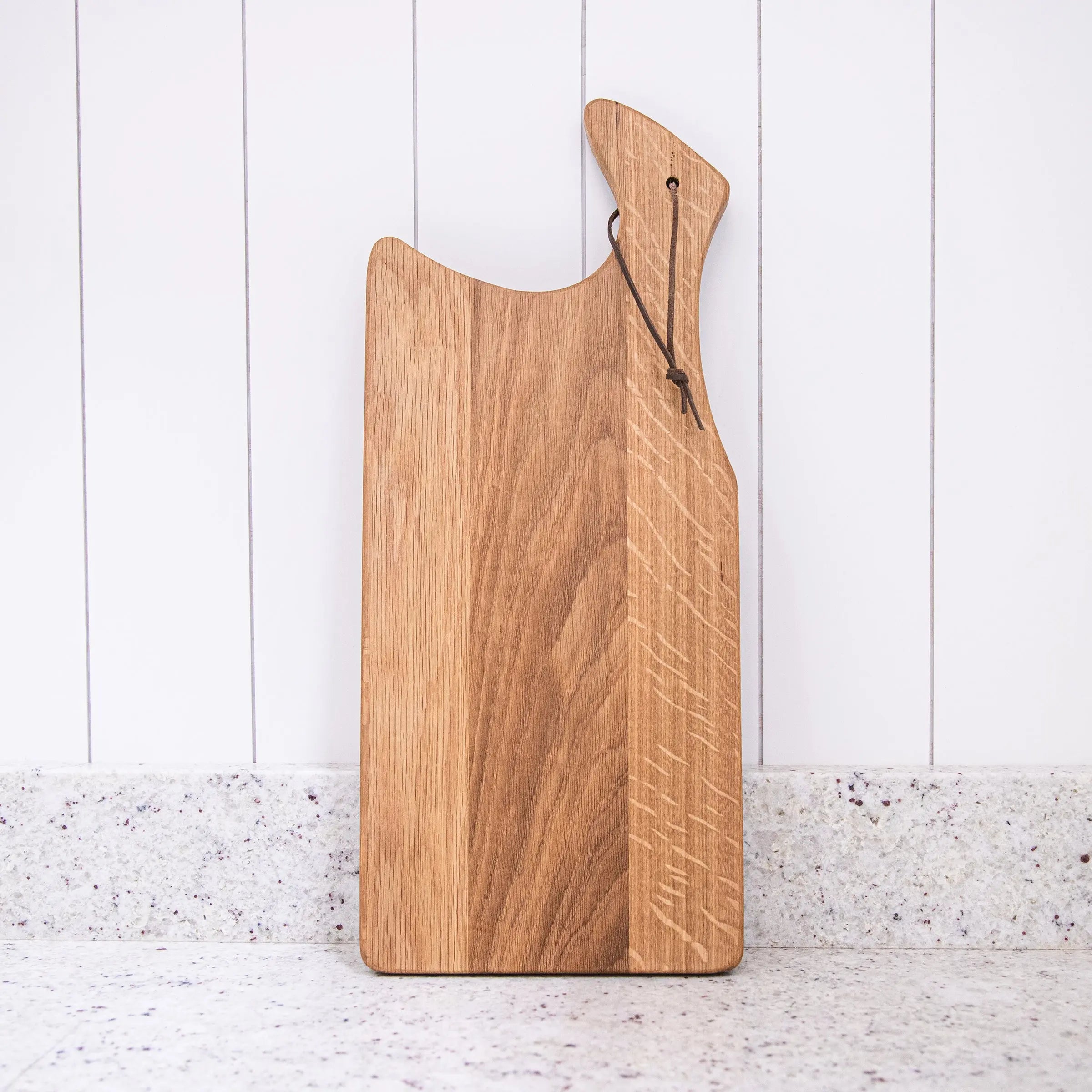 Wooden cutting board with a handle on a white wooden background